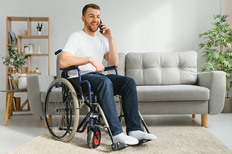 A man in a wheelchair on the phone.  He is happy and excited.